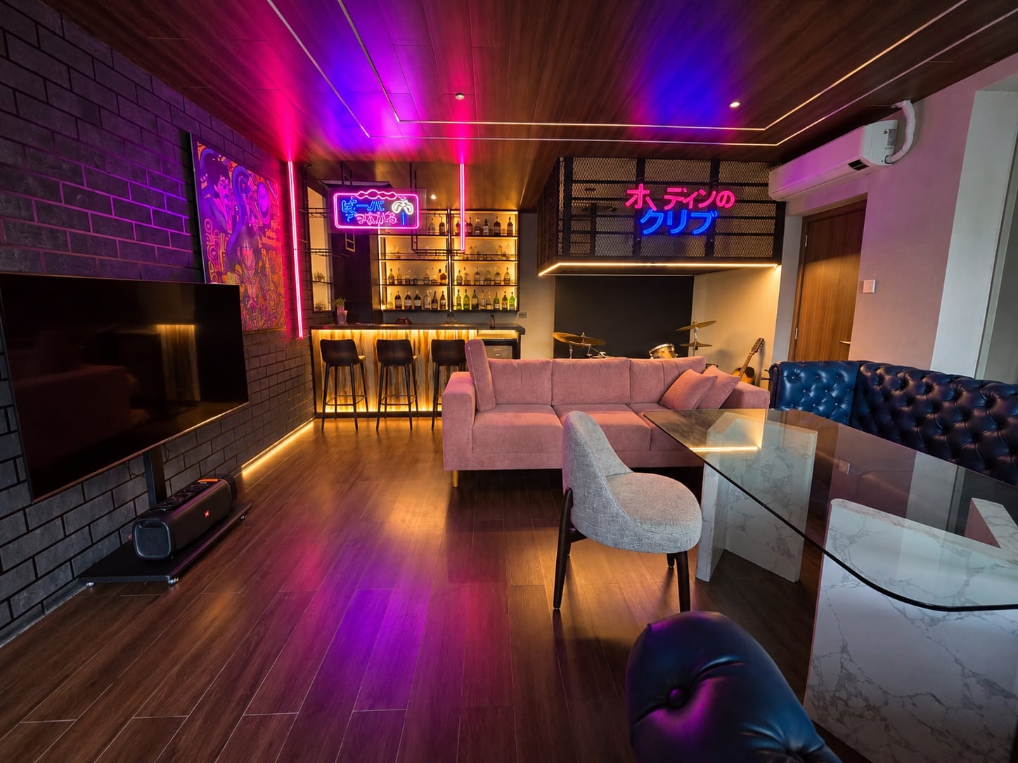 The whole KTV lounge: big screen, sofas and the neon-lit bar