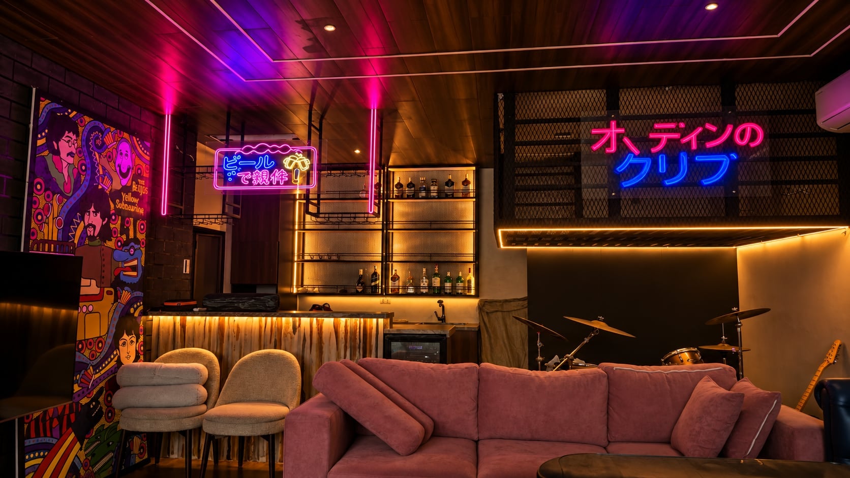 The KTV lounge with its neon-lit bar, sofas and drum kit